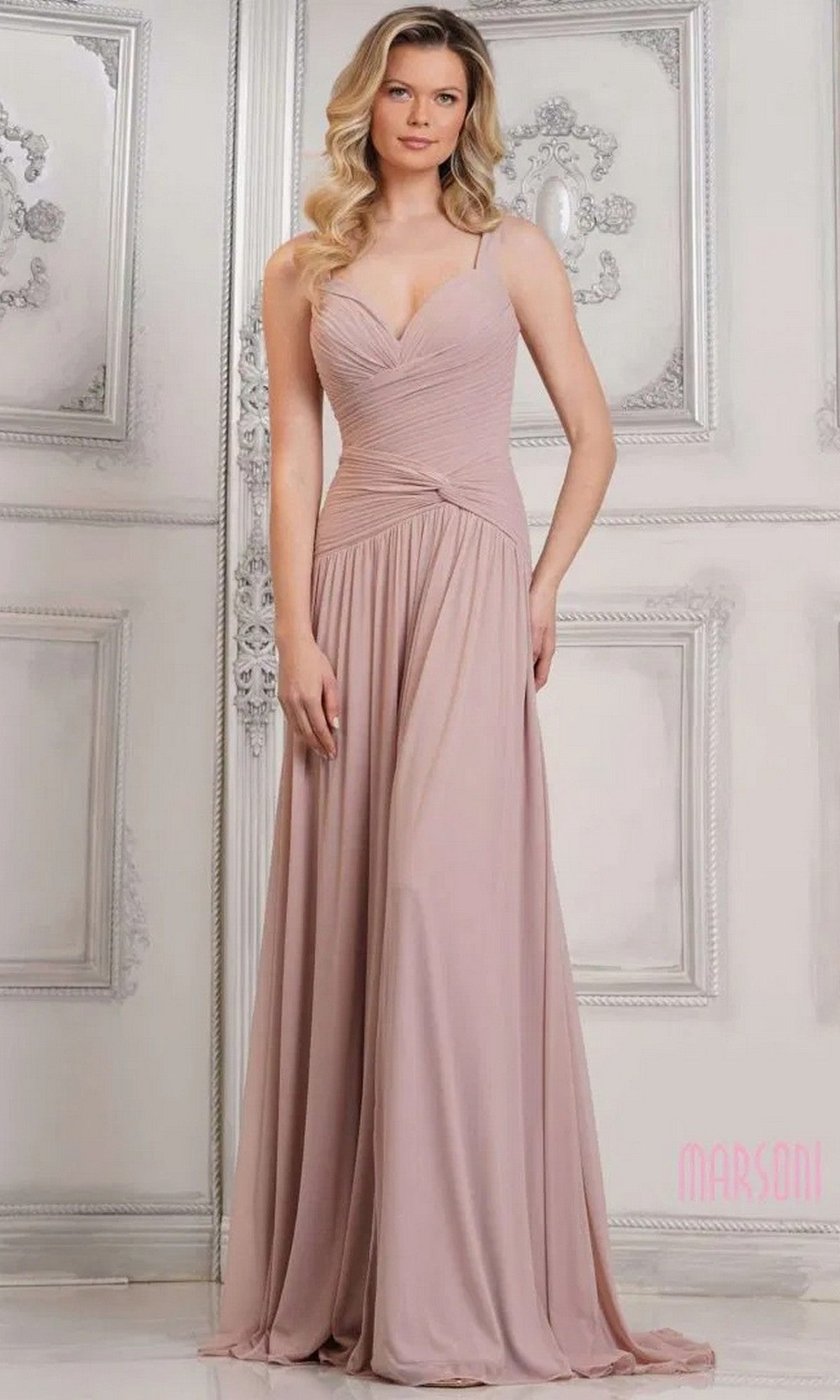 A woman wears the Marsoni MV1316, a pale pink, floor-length sleeveless formal dress with a ruched bodice, standing in an ornate room with white panel walls.